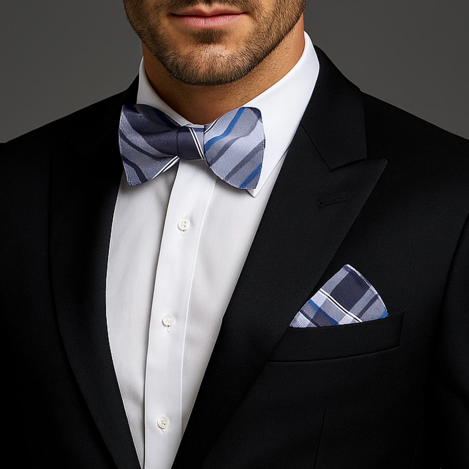 Man wearing a black tuxedo with a white shirt, blue patterned bow tie, and matching pocket square.