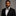 Man wearing a black suit with a patterned bow tie against a gray background