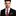 Man wearing a black suit with a red striped tie and matching pocket square on a white background