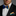 Man wearing a black suit with a colorful bow tie and pocket square against a gray background