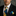 Man wearing a black suit with a colorful tie and pocket square against a gray background