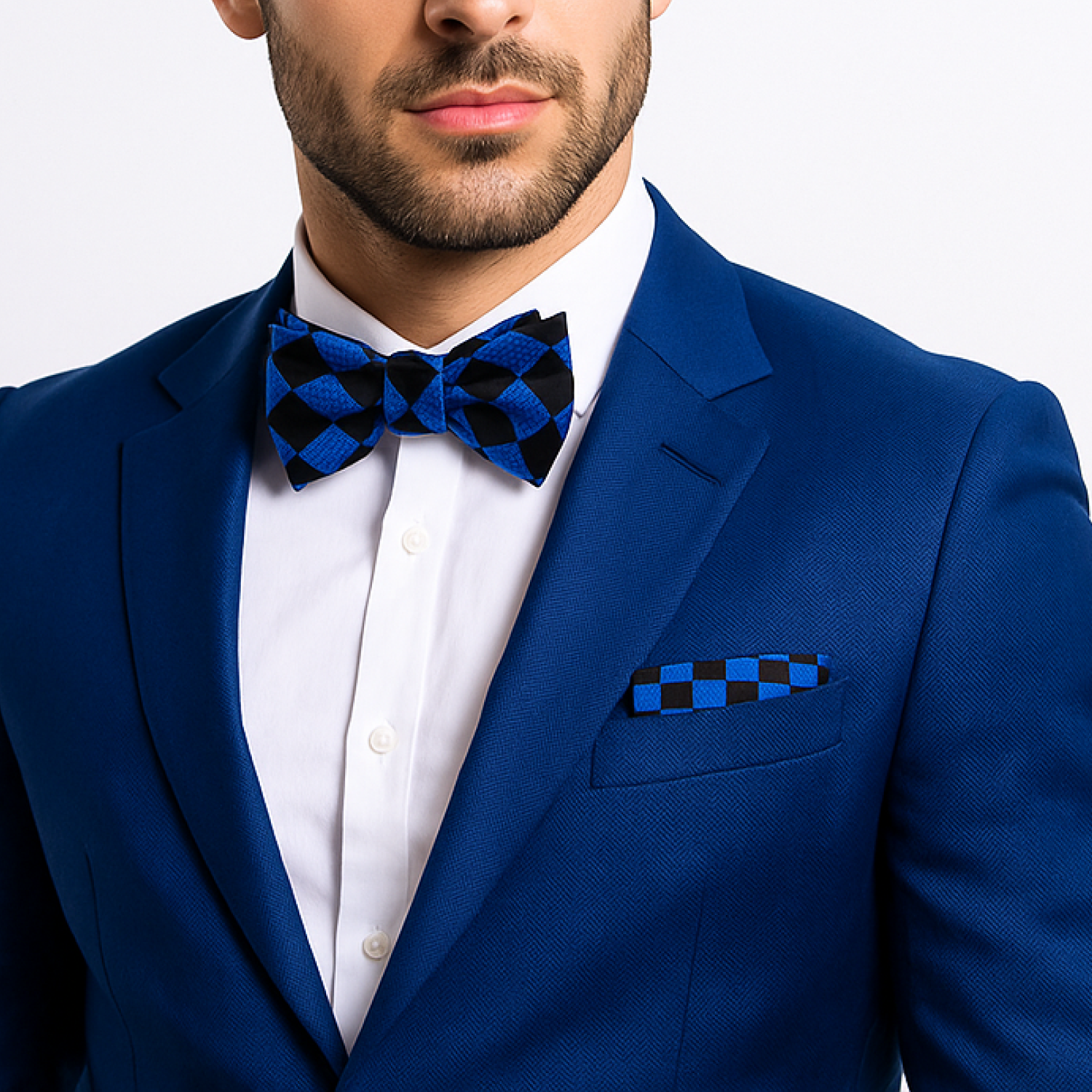 Man wearing a blue suit with a checkered bow tie and pocket square on a light gray background