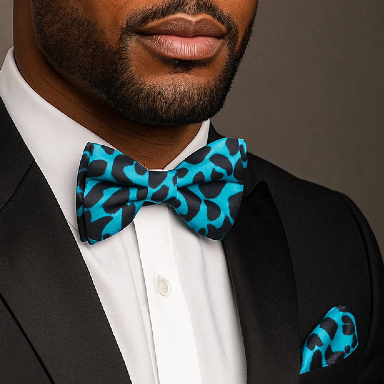 Man wearing a black suit with a blue and black patterned bow tie and matching pocket square.