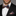 Man wearing a black suit with a colorful bow tie and pocket square against a gray background