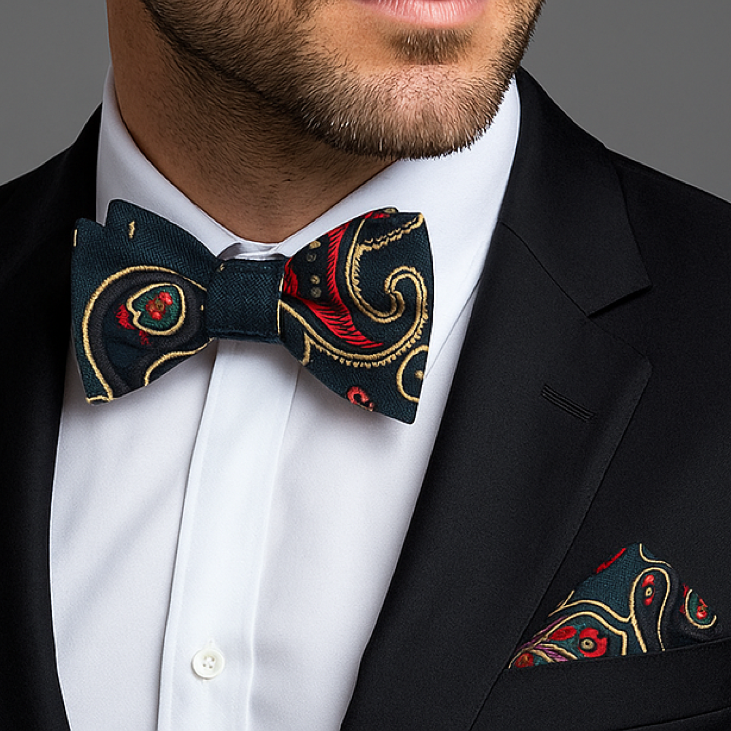 Man wearing suit with green, red and yellow paisley bow tie and square