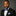 Man wearing a black suit with a blue bow tie and pocket square on a gray background