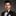 Man wearing a black tuxedo with a bow tie against a gray background