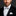 Man wearing a black tuxedo with a white shirt and polka dot bow tie and pocket square on a dark background