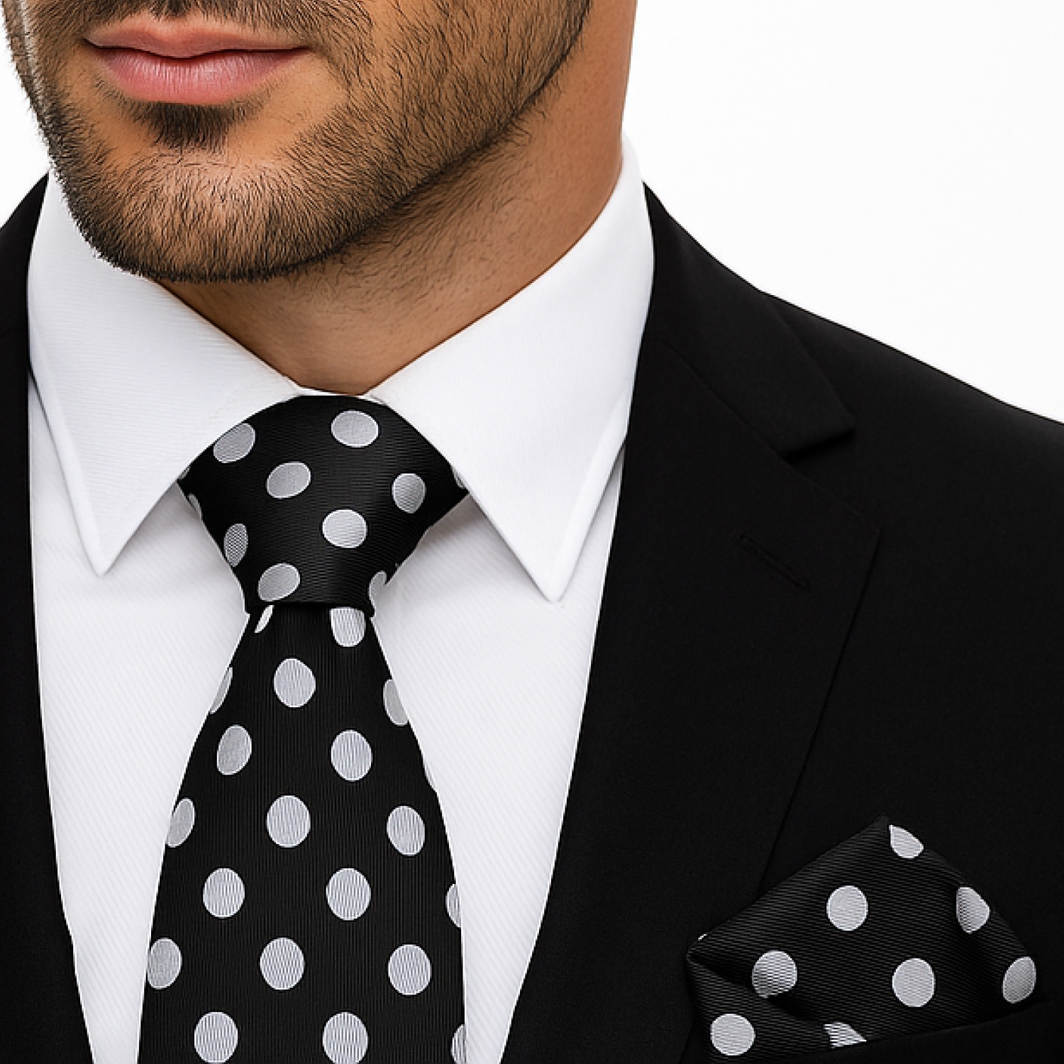 Man wearing a black suit with a light grey polka dot tie and pocket square.