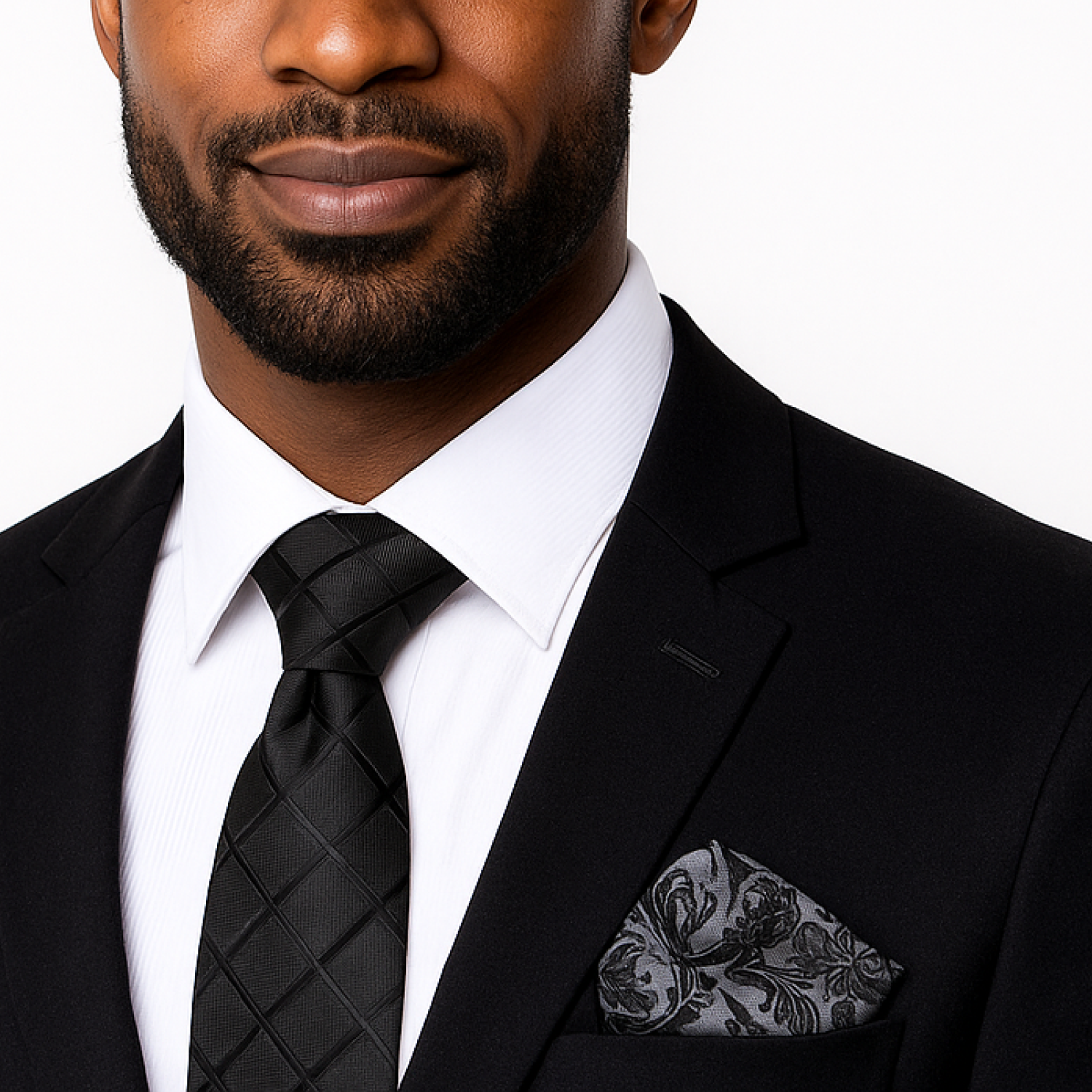 Man wearing a black suit with a white shirt and black tie on a plain background