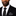 Man wearing a black suit with a white shirt and black tie on a plain background