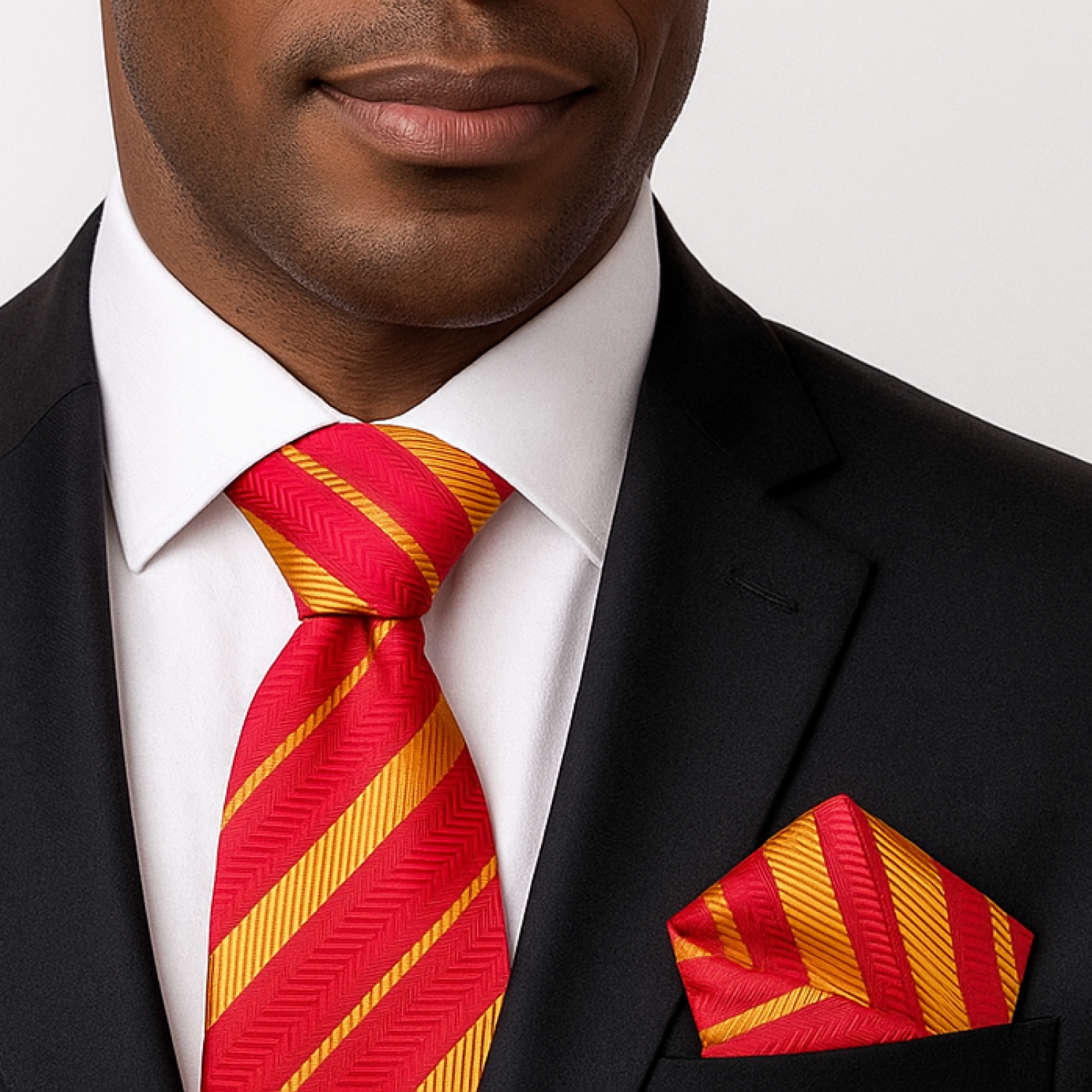 Man wearing a black suit with a red and yellow striped tie and pocket square.