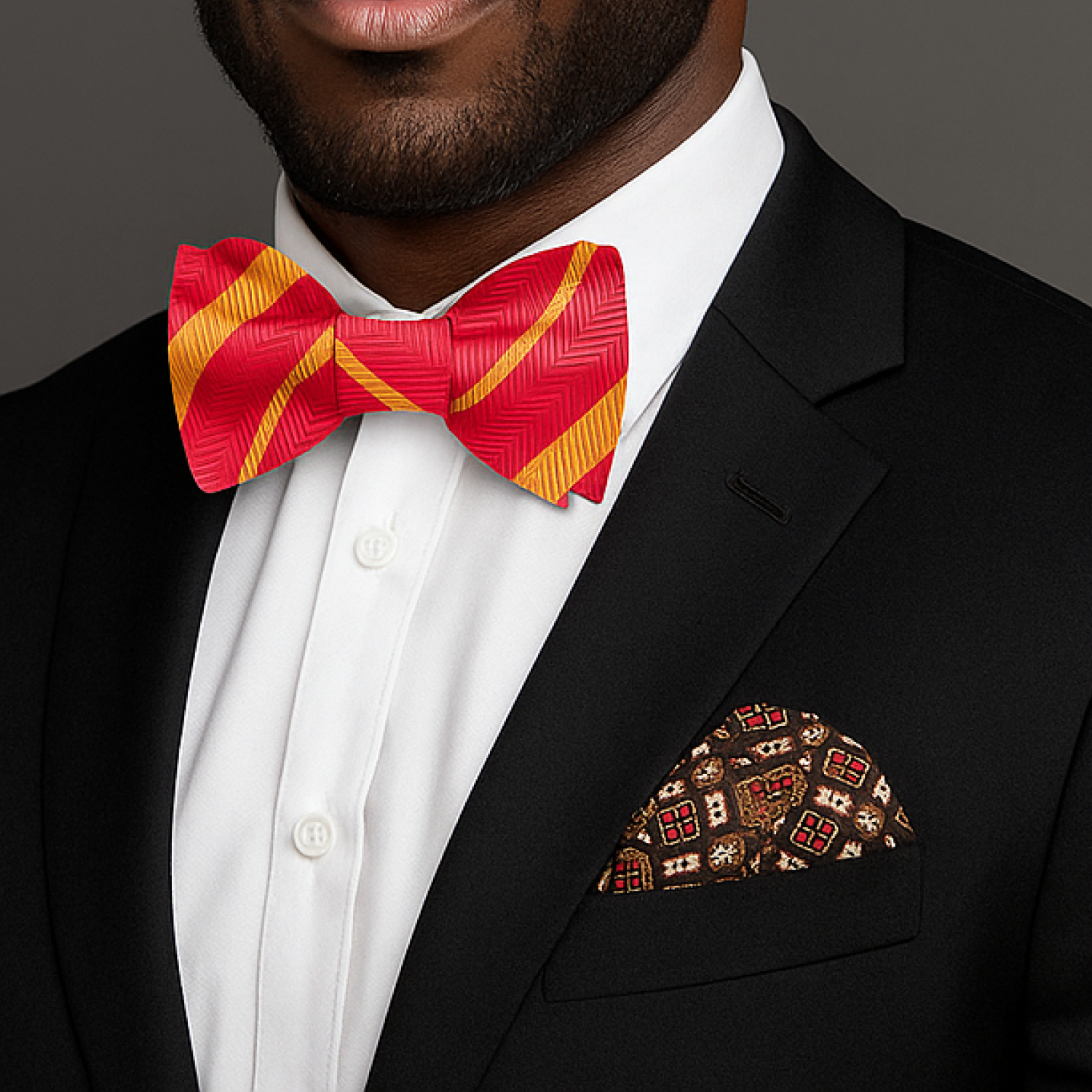 Man wearing a black suit with a red and yellow bow tie and patterned pocket square.