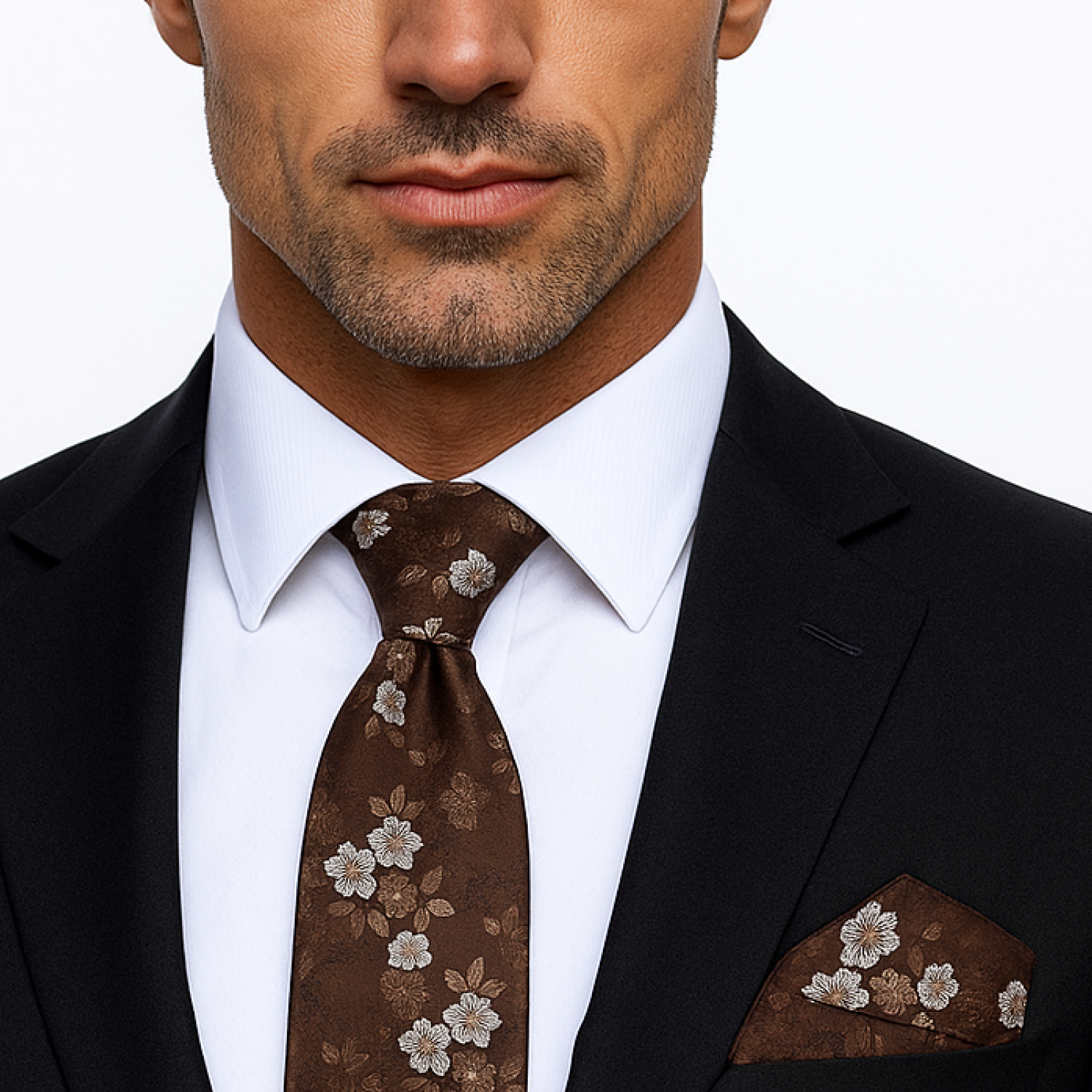 Man wearing a black suit with a white shirt, brown floral tie, and matching pocket square.