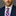 Man wearing a navy suit with a pink and blue striped tie against a gray background