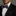 Man wearing a colorful bow tie and black suit jacket with a gray background