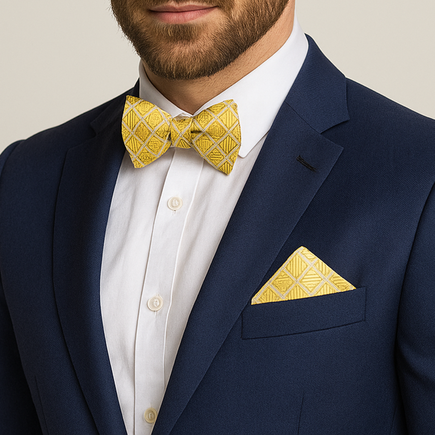 Man wearing a navy suit with a yellow bow tie and pocket square against a neutral background