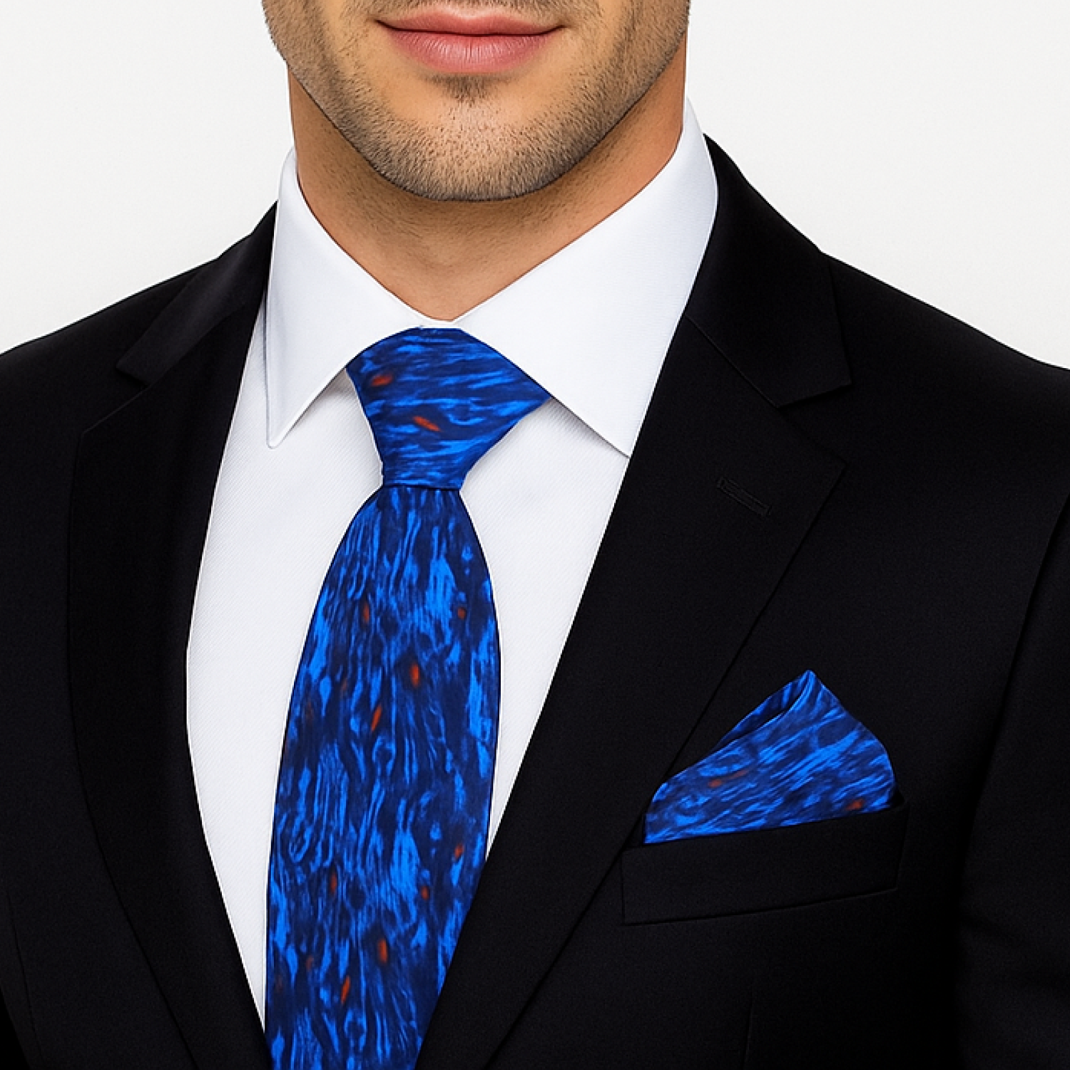 Man wearing a black suit with a blue patterned tie and pocket square on a white background