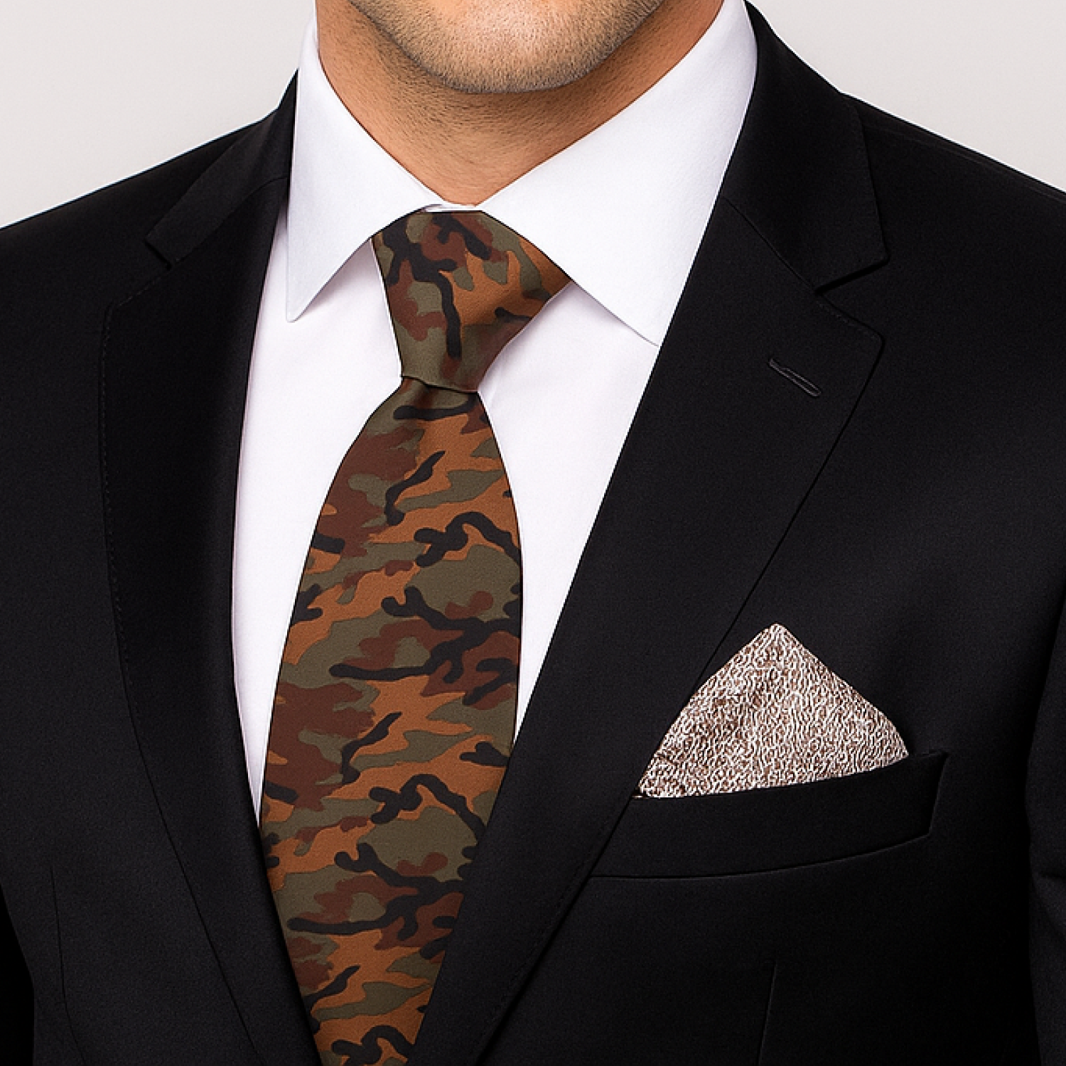 Man wearing a black suit with a white shirt, camouflage tie, and patterned pocket square.