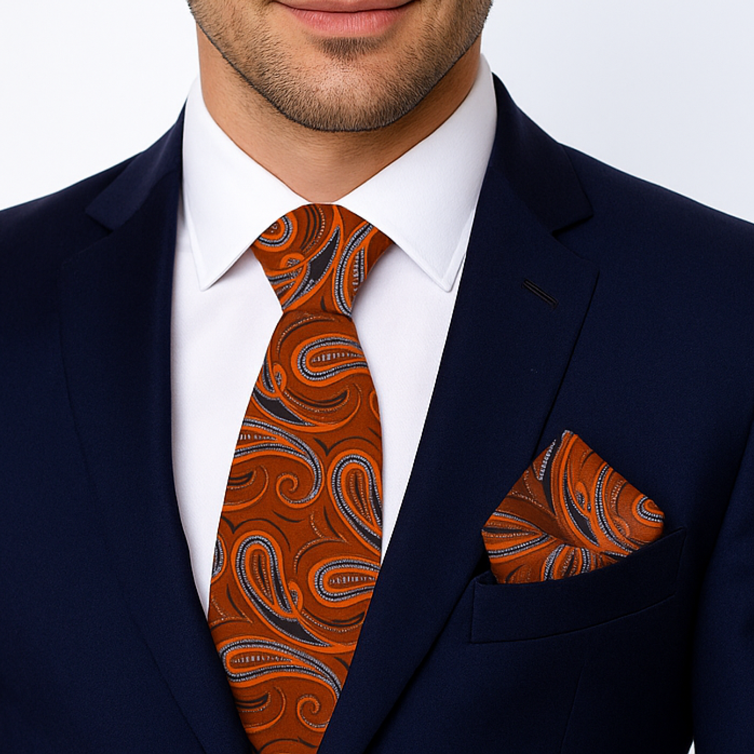 Man wearing a navy suit with a white shirt, orange paisley tie, and matching pocket square.