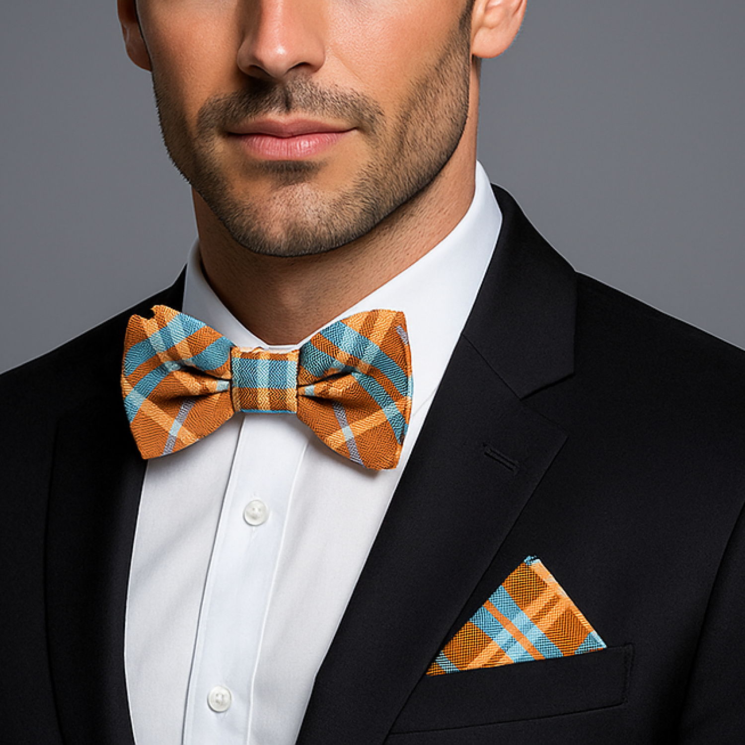 Man wearing a black suit with an orange and blue checkered bow tie and pocket square.
