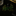 Green and gold brooch on a black surface with a glass object in the corner