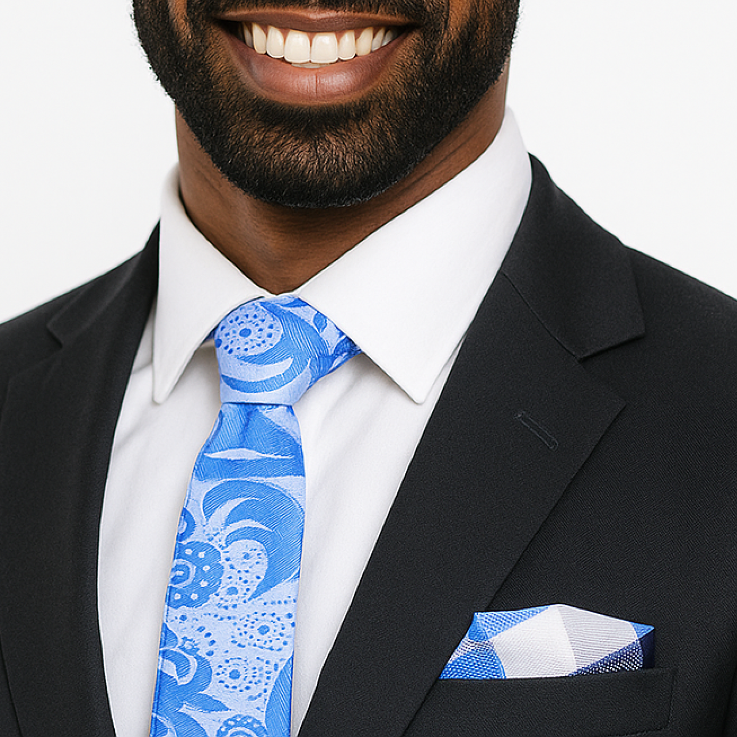 Man wearing a black suit with a blue patterned tie and pocket square on a white background