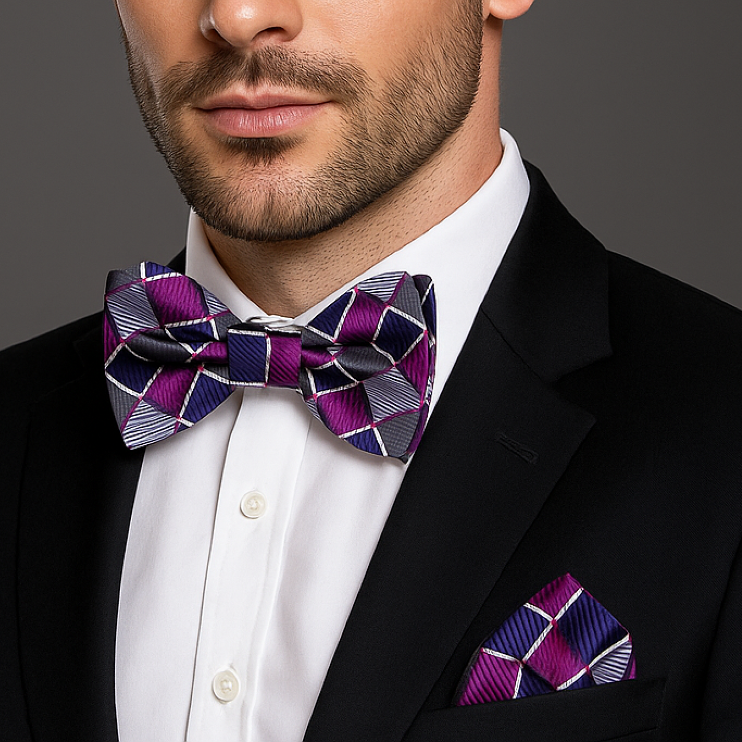 Man wearing a black suit with a purple and blue checkered bow tie and pocket square.