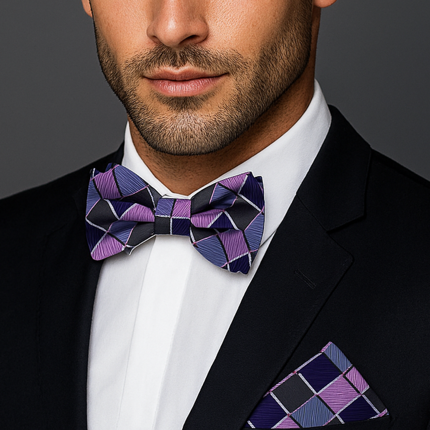 Man wearing a black suit with a purple geometric bow tie and matching pocket square.