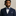 Man wearing a navy suit with a patterned bow tie and pocket square against a beige background