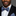 Man wearing a black suit with a colorful bow tie and pocket square against a gray background