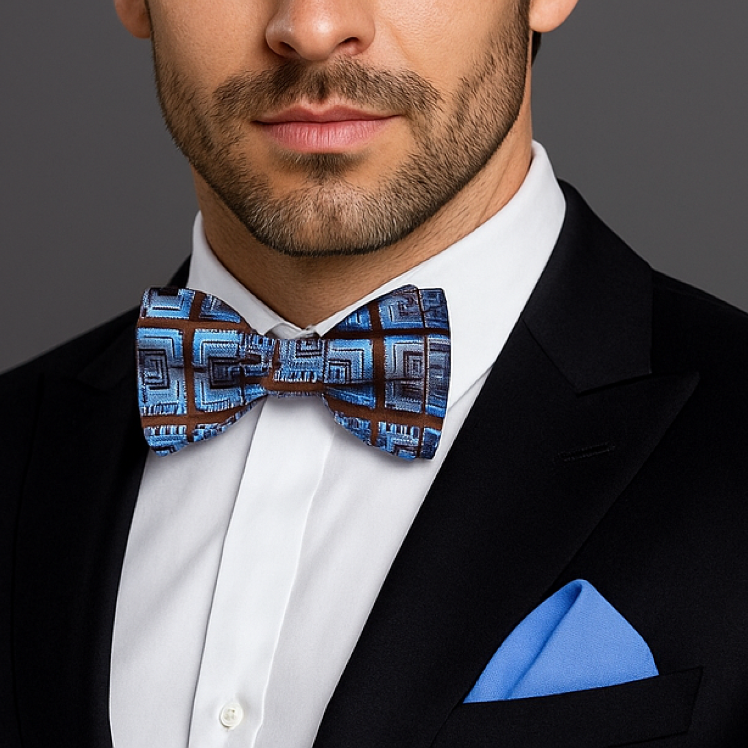 Man wearing a black suit with a blue geometric bow tie and pocket square.