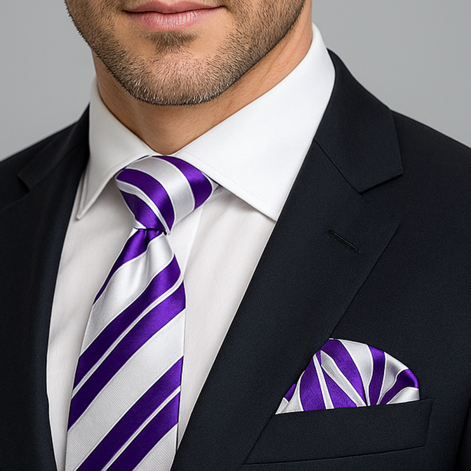 Man wearing a black suit with a white shirt, purple and white striped tie, and matching pocket square.