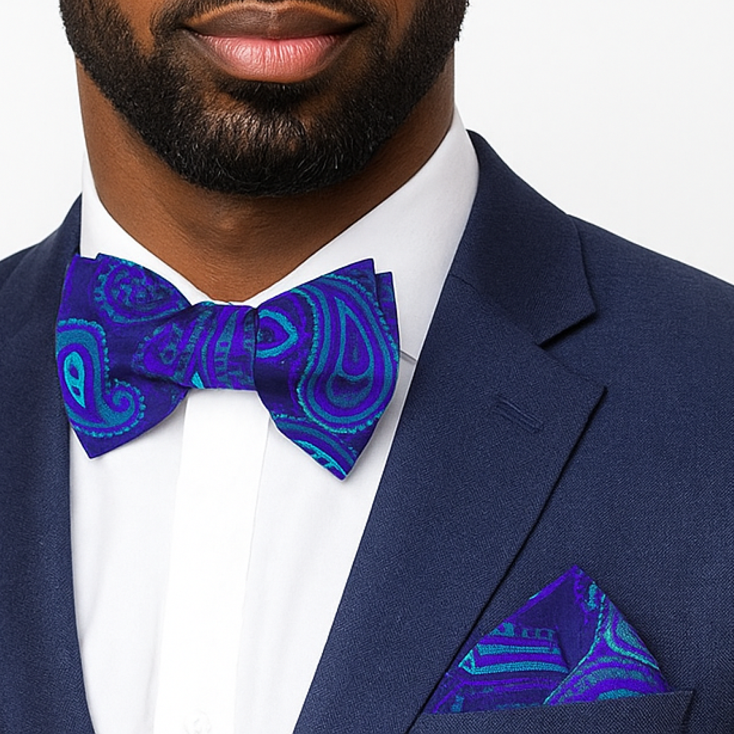 Man wearing a navy suit with a blue paisley bow tie and pocket square.
