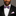 Man wearing a black tuxedo with a grey and pink bow tie and pocket square on a gray background