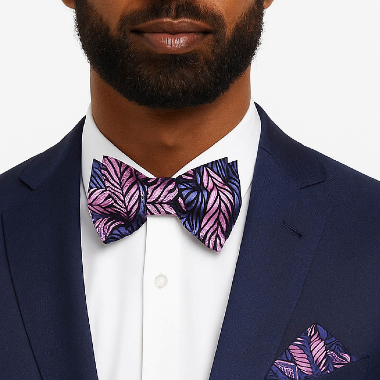 Man wearing a navy suit with a pink and purple leaf-patterned bow tie and pocket square.