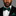 Man wearing a black suit with a green patterned bow tie and pocket square against a gray background