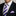 Man wearing a black suit with a white shirt, purple striped tie, and light purple pocket square.