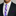 Man wearing a black suit with a white shirt and a purple polka dot tie.