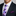Man wearing a black suit with a white shirt, purple polka dot tie, and purple pocket square.