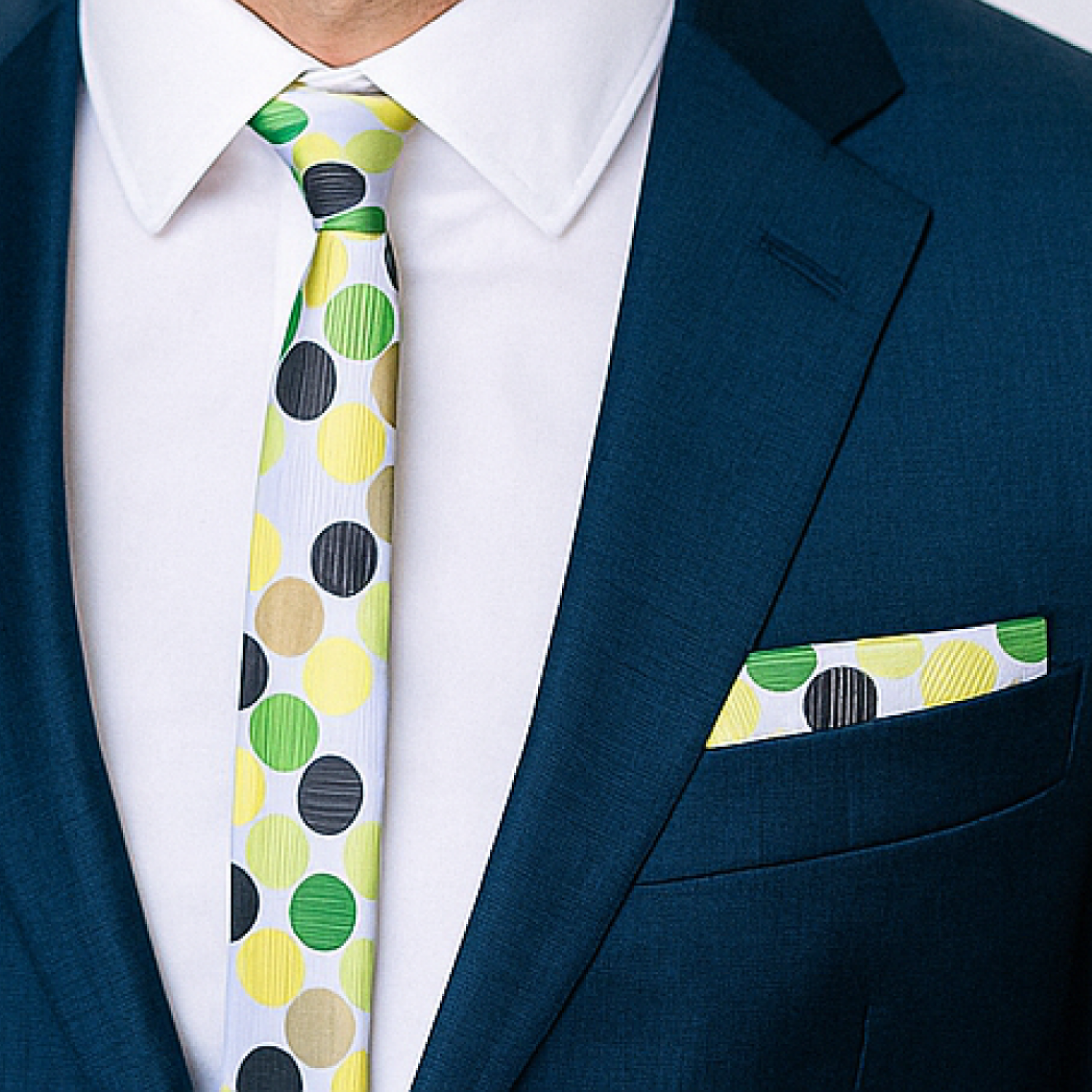 Man wearing a blue suit with a colorful polka dot tie and matching pocket square.