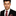 Man wearing a black suit with a red and black striped tie on a white background