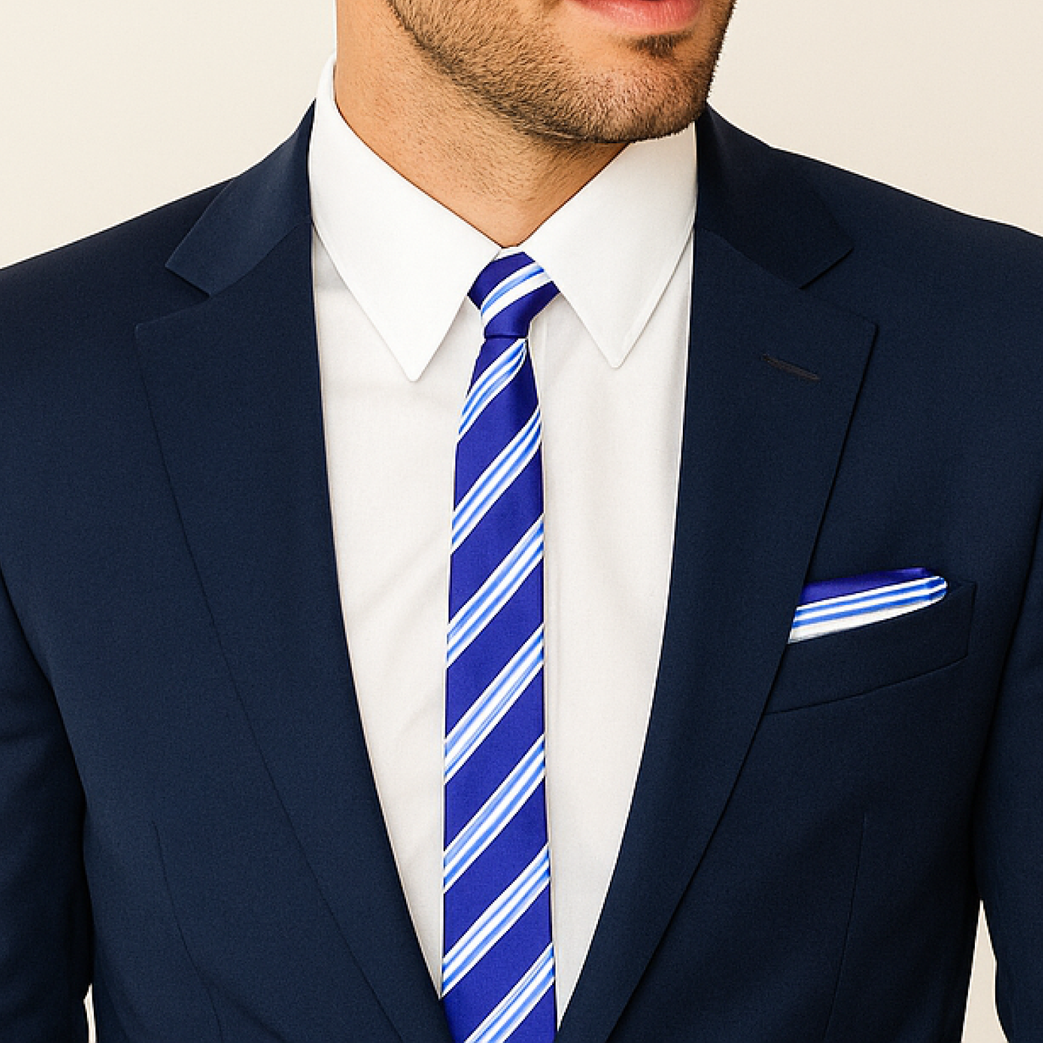 Man wearing a navy suit with a blue and white striped tie and pocket square.