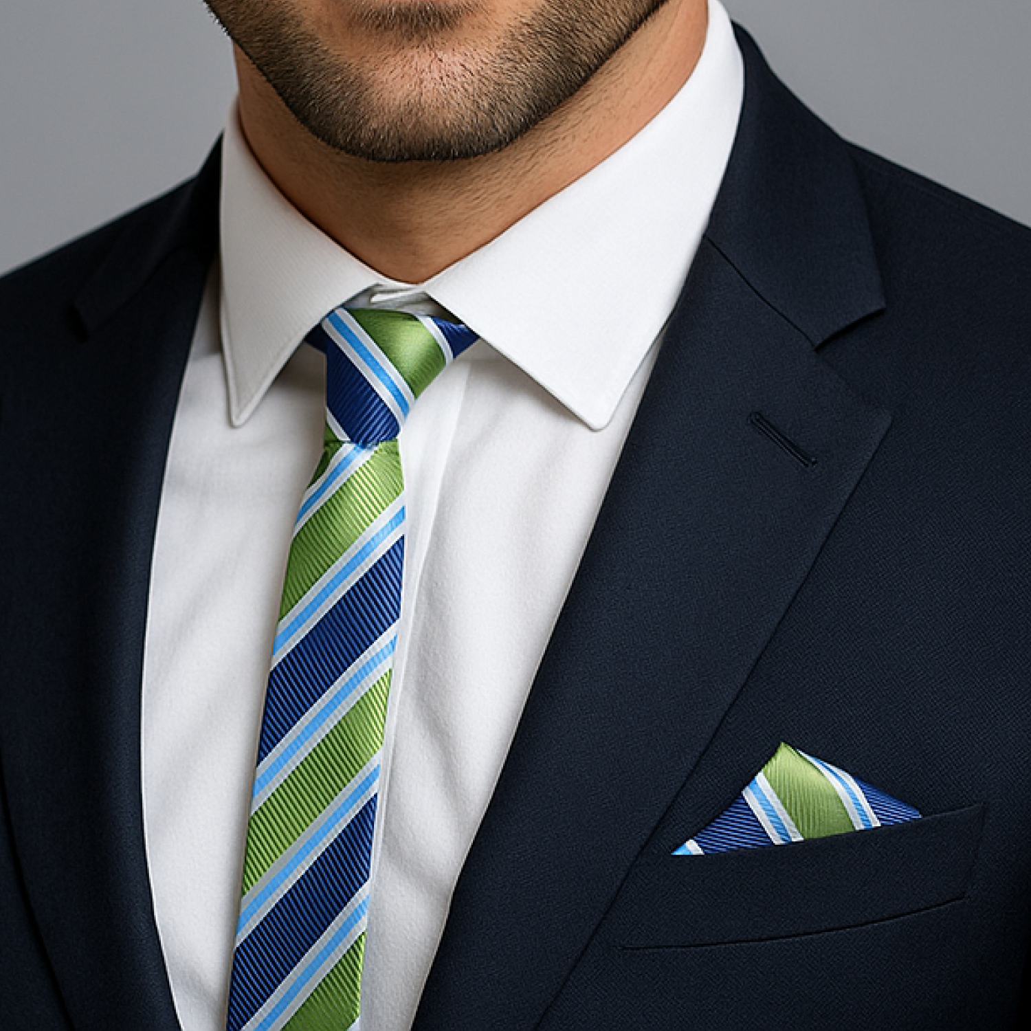 Man wearing a navy suit with a white shirt, green and blue striped tie, and matching pocket square.