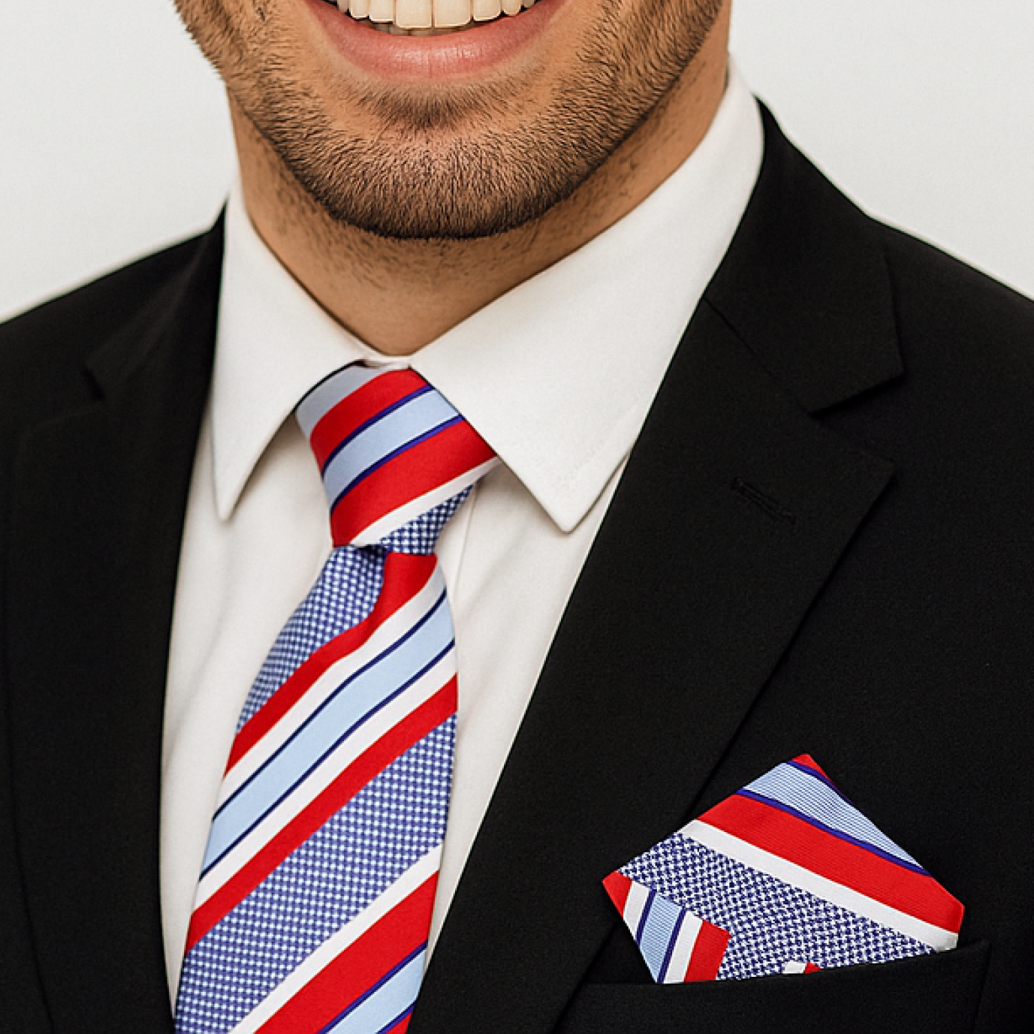 Man wearing a black suit with a red, white, and blue striped tie and pocket square.