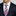 Man wearing a navy suit with a colorful striped tie and blue white dot square