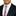Man wearing a black suit with a white shirt, red, white, and blue striped tie, and a blue dot pocket square.