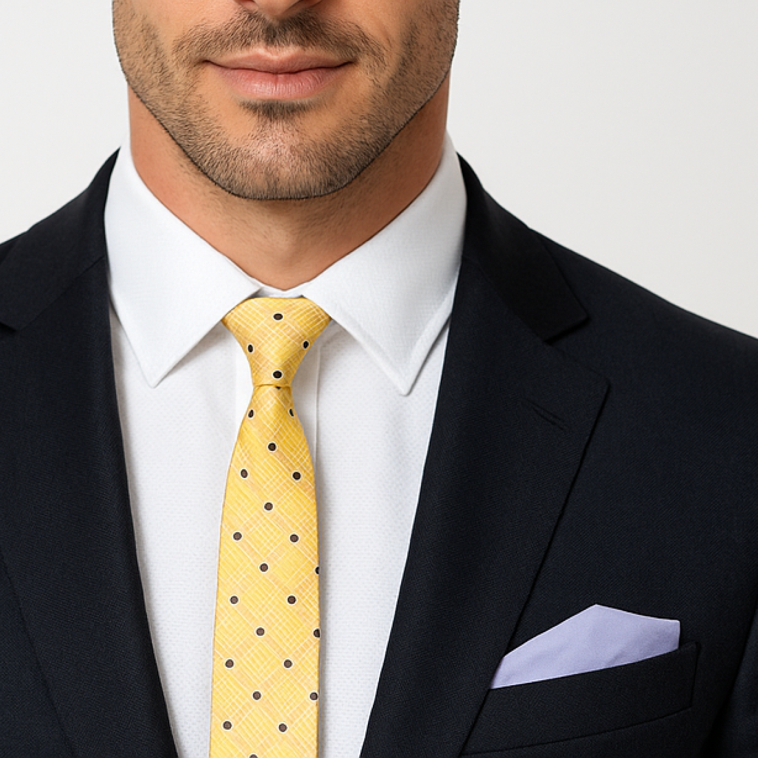 Man wearing a black suit with a white shirt and yellow polka dot tie.