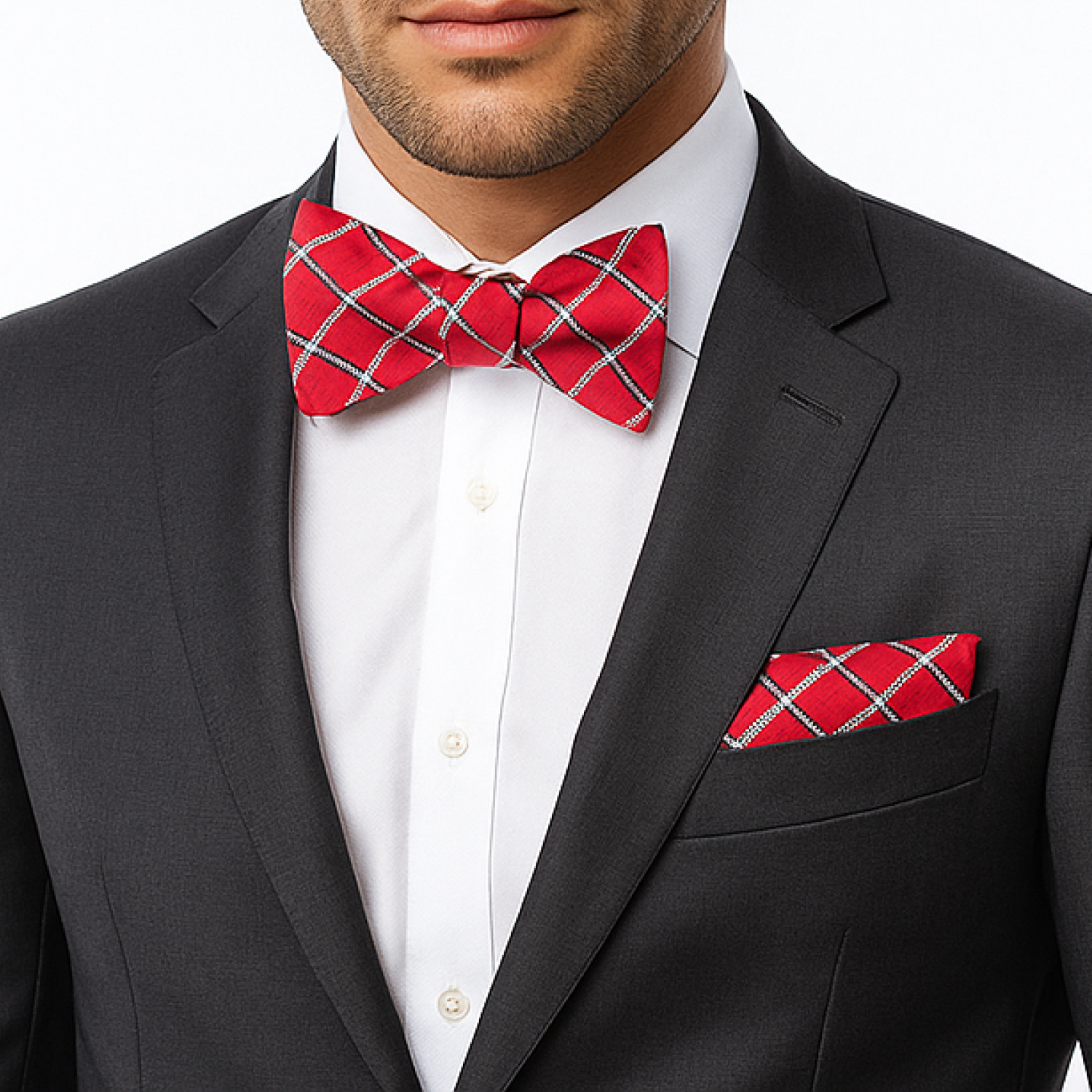 Man wearing a black suit with a red plaid bow tie and pocket square on a white background