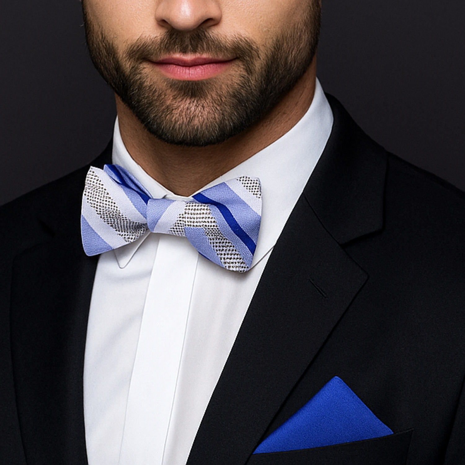 Man wearing a black suit with a blue and white patterned bow tie and matching pocket square.